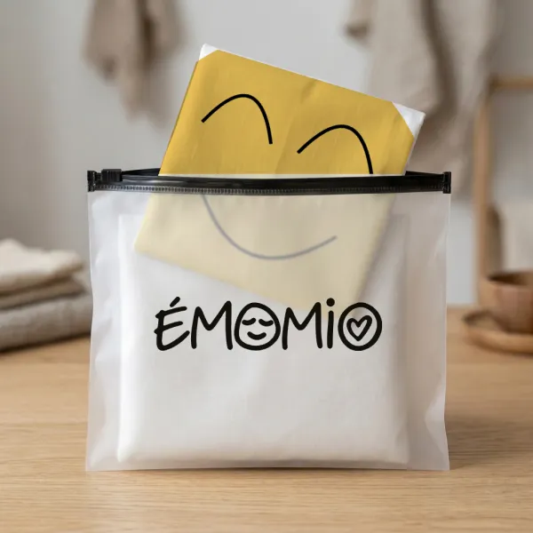 Une housse Émomio pliée dans sa pochette translucide marquée du logo Émomio.